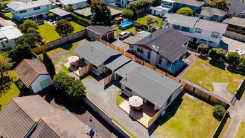An aerial view of a residential area with multiple houses, a central house with a patio, and a fenced yard.