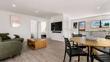 A modern living room with a sofa, a coffee table, and a dining area with a table and chairs.