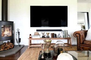 A living room with a fireplace, a television mounted on the wall, and a wooden coffee table with various items.