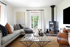 A living room with a sofa, a glass coffee table, a fireplace, and a TV.