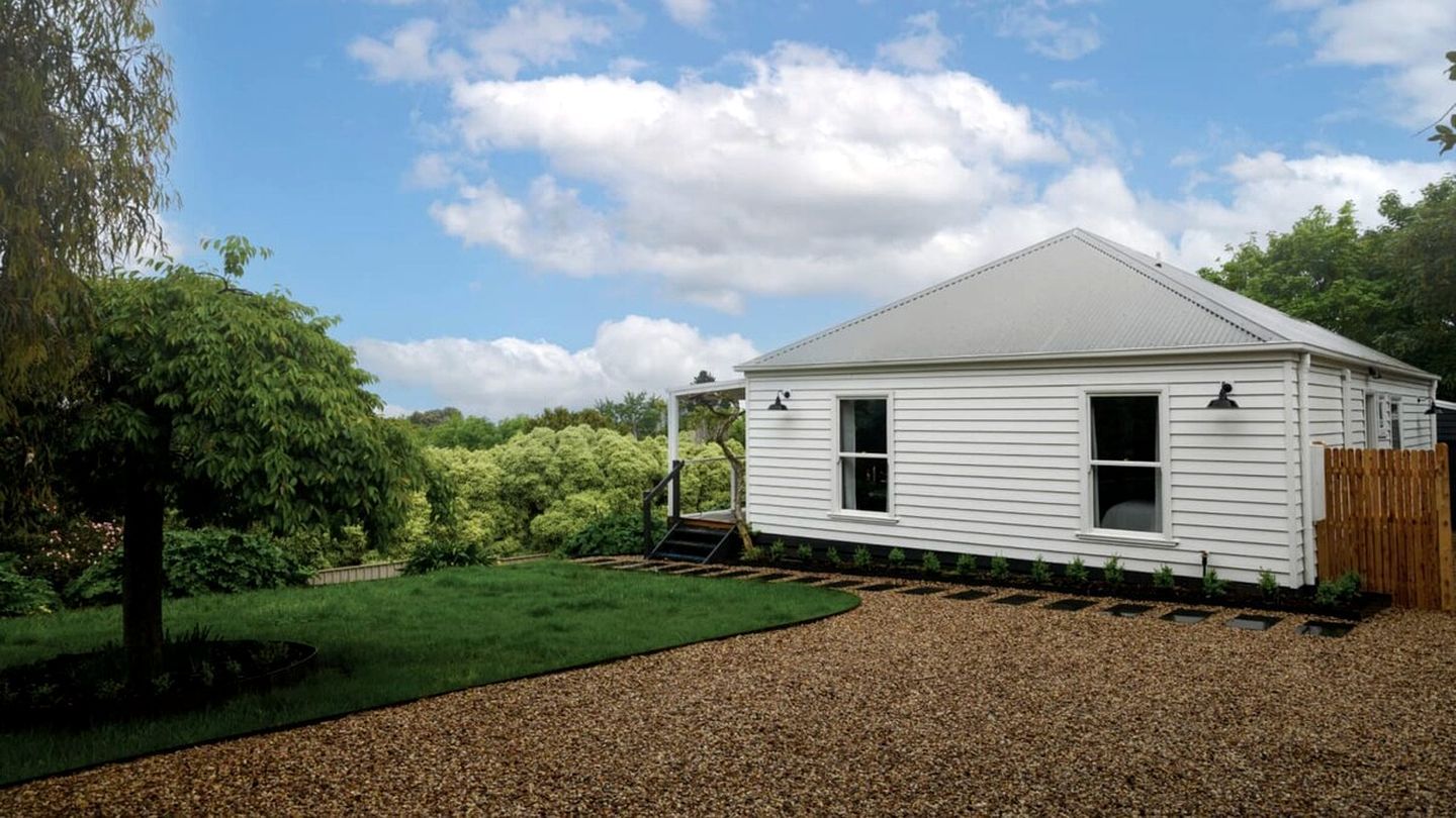 A single-story house with a sloped roof, a front porch, and a gravel driveway.