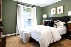 A bedroom with a bed, a nightstand, a lamp, a window with curtains, and a wall with two framed pictures. - Incredible Cabin with Fire Pit and Barbecue in Daylesford, Victoria (Daylesford)