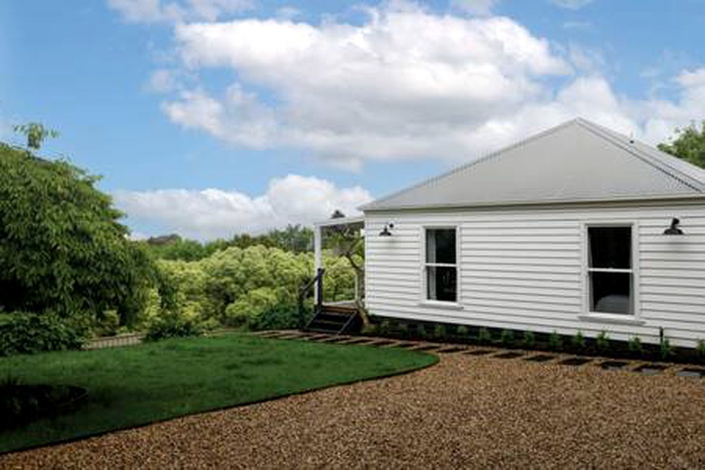A single-story white building with a sloped roof, a covered porch, and a gravel driveway.