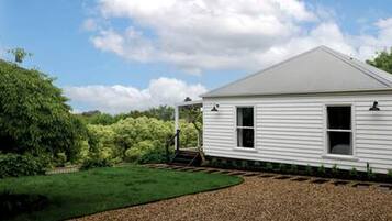 A single-story white building with a sloped roof, a covered porch, and a gravel driveway.