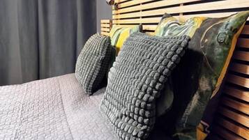 A bed with a quilted cover, a wooden headboard, and decorative pillows.