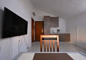 A modern kitchen with a flat-screen TV, wooden cabinets, and a dining area with a table and chair. - UNILOFT - Uni Area - Policlinic Area (Modena)