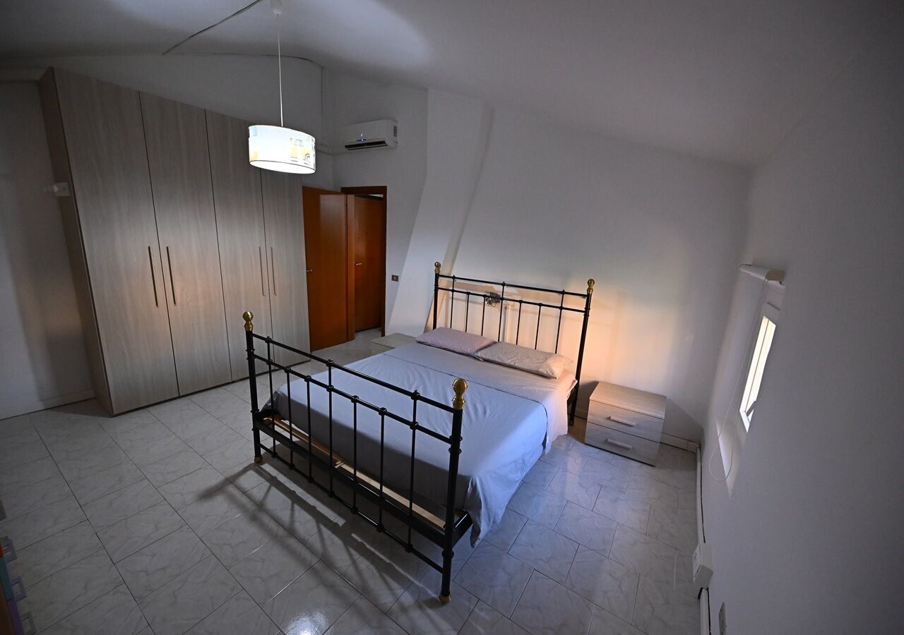 Ein Schlafzimmer mit Bett, Kleiderschrank und kleinem Fenster.