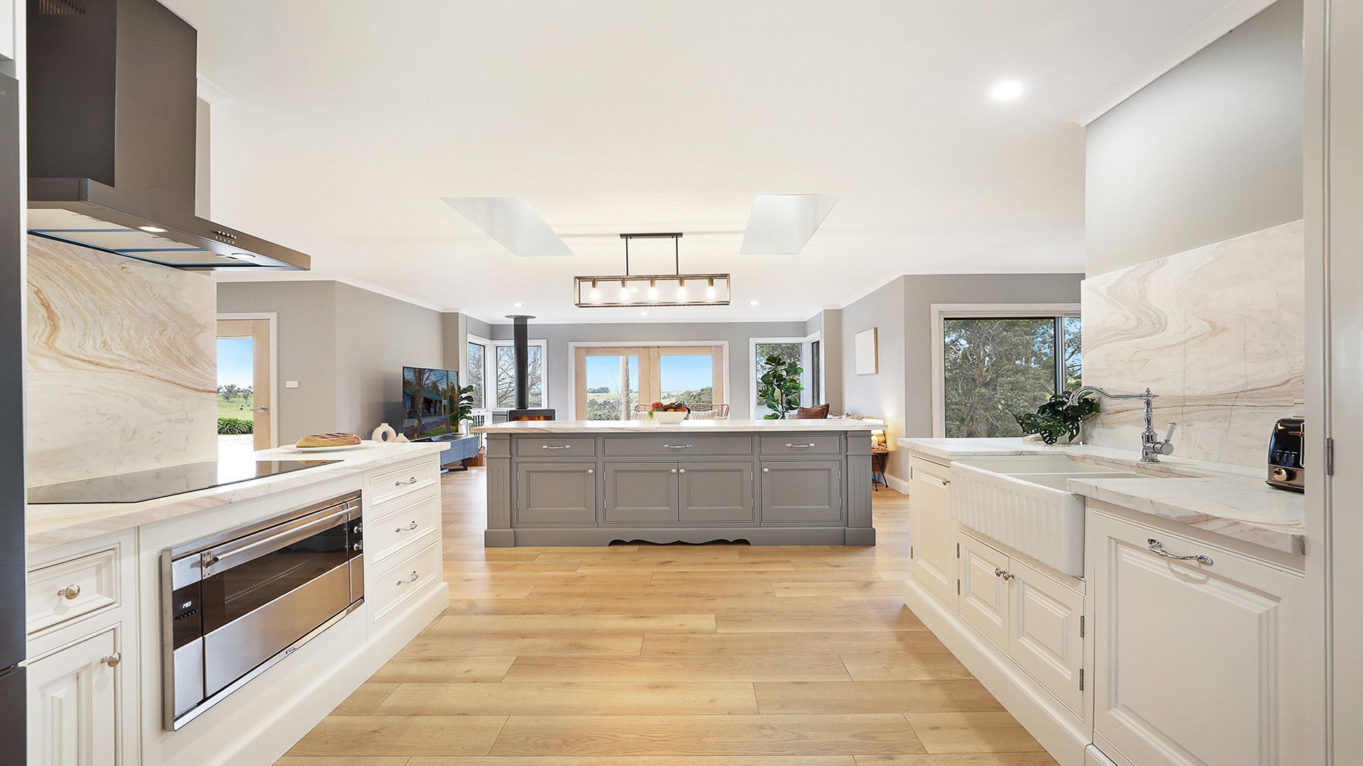 A modern kitchen with a central island, built-in appliances, and large windows.