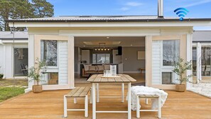 Una casa moderna con terraza de madera, comedor y cocina a la vista.