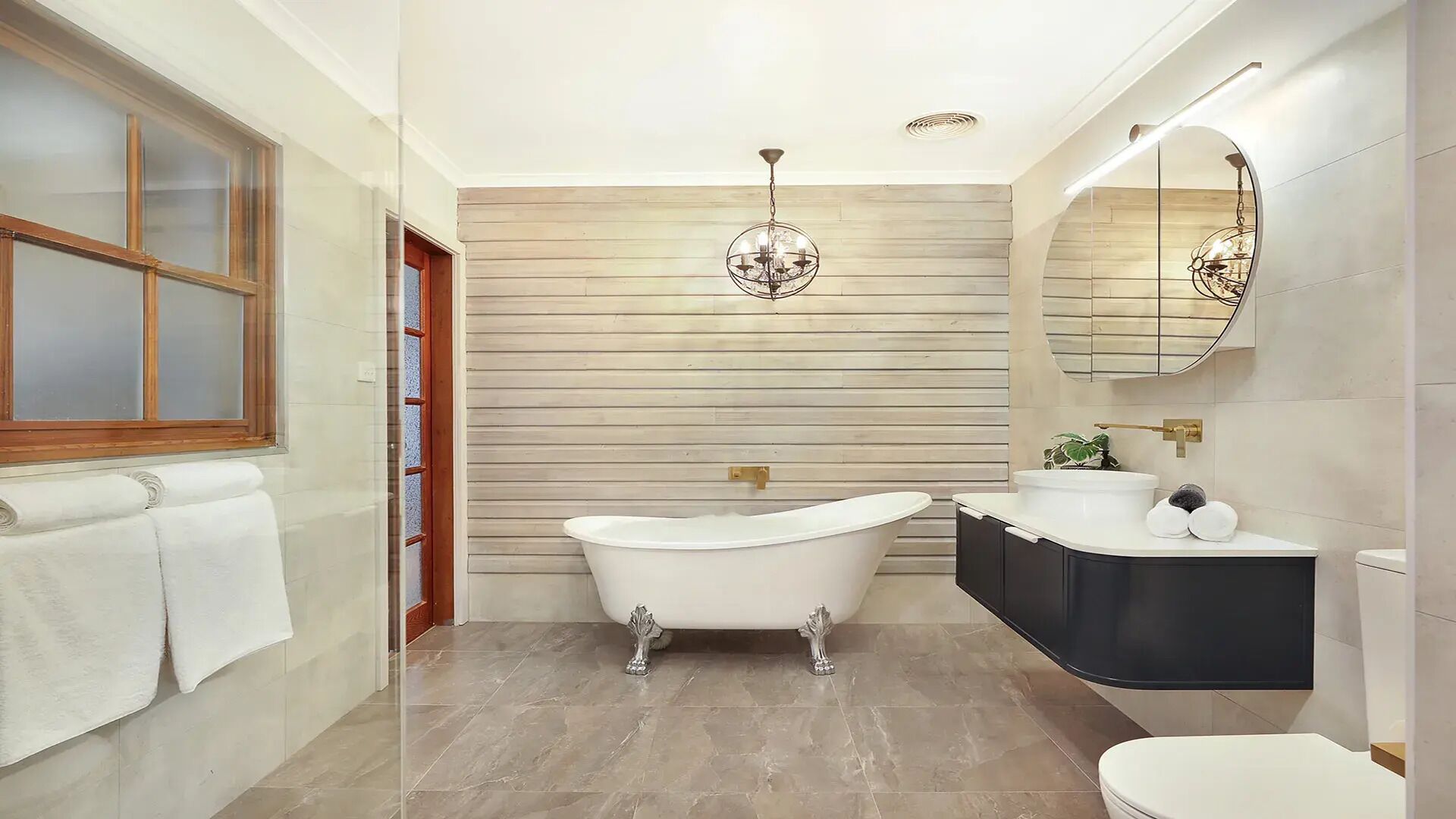 A bathroom with a freestanding bathtub, a vanity with a mirror, and a toilet.