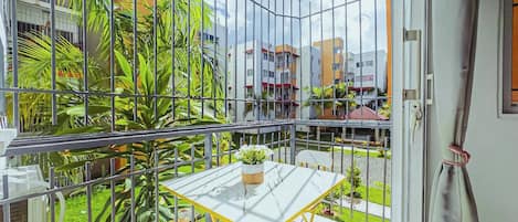 Ein Balkon mit Glasveranda, einem kleinen Tisch, einem Stuhl und einem Blumentopf.