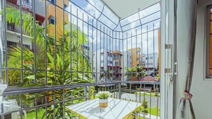 A balcony with a glass enclosure, a small table, a chair, and a potted plant. - Airport Oasis 10 min From Las Americas (Santo Domingo Este)