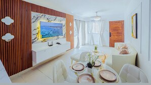 A modern living room with a dining area, a large flat-screen TV, and a wooden accent wall. - Airport Oasis 10 min From Las Americas (Santo Domingo Este)
