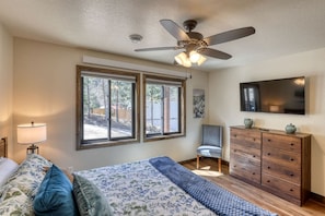 A bedroom with a bed, a dresser, a chair, a ceiling fan, and a TV on the wall. - Luxury Black Hills Chalet with Hot Tub Near Mount Rushmore, Keystone SD (Keystone)