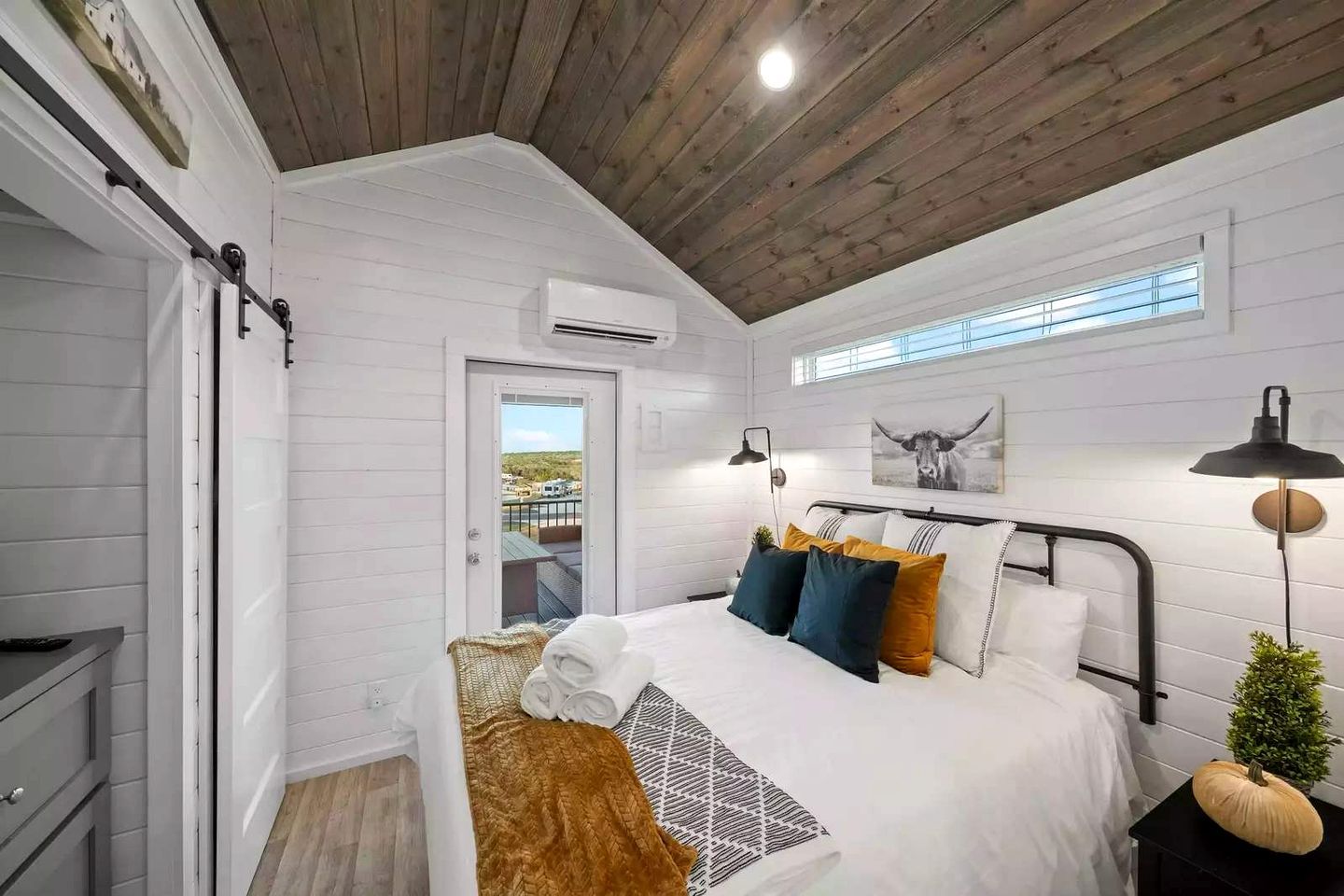 Une chambre à coucher avec un lit, des lampes de chevet, une fenêtre donnant sur un paysage agréable et une porte.