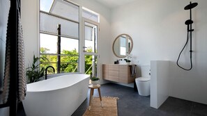 A modern bathroom with a freestanding bathtub, a toilet, a sink with a mirror, and a shower.