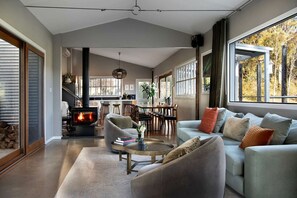 A modern living room with a fireplace, comfortable seating, and large windows. - Amazing Villa with Swimming Pool and Lake Access in Hepburn, Victoria (Hepburn)