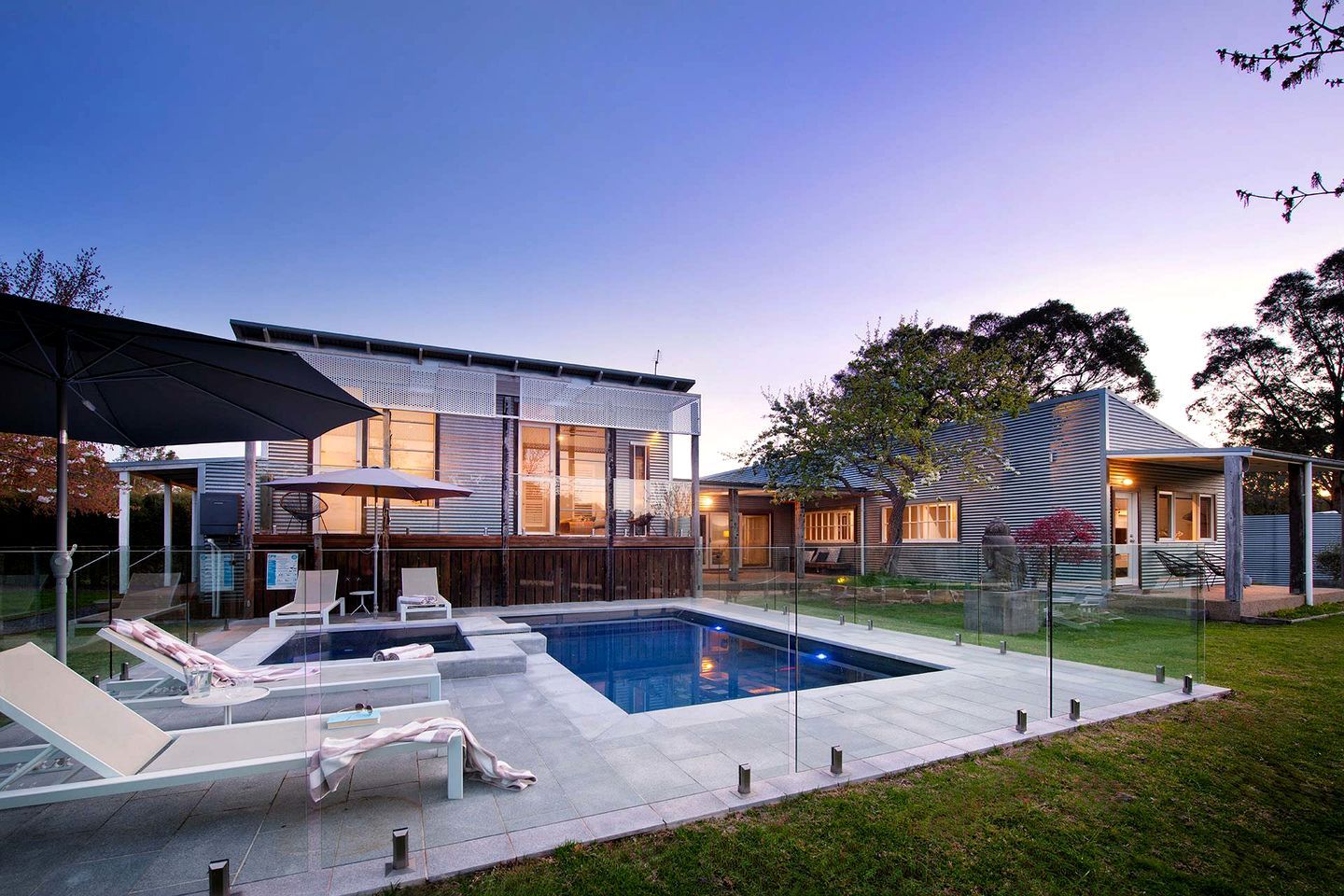 A modern house with a swimming pool, outdoor seating, and a covered patio area.