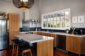 A modern kitchen with a central island, wooden cabinets, stainless steel appliances, and a large window providing natural light.