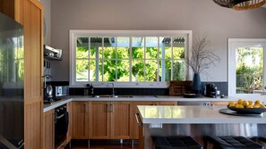 A modern kitchen with wooden cabinets, a large window, and a central island with stools.