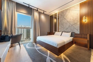 Una camera d'albergo moderna con un letto grande, una scrivania e vista sulla città.