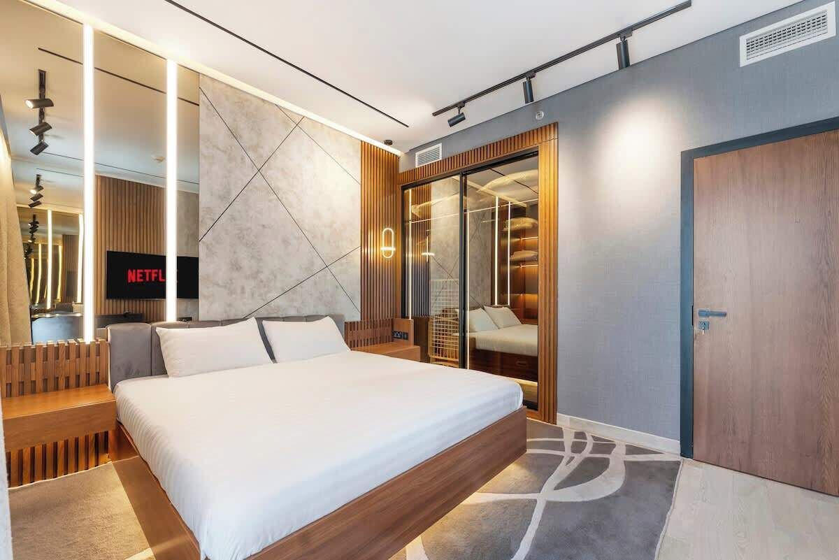 Une chambre moderne avec un grand lit, un dressing et un téléviseur affichant le logo de « NETFLIX ».
