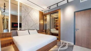 Une chambre moderne avec un grand lit, un dressing et un téléviseur affichant le logo de « NETFLIX ».
