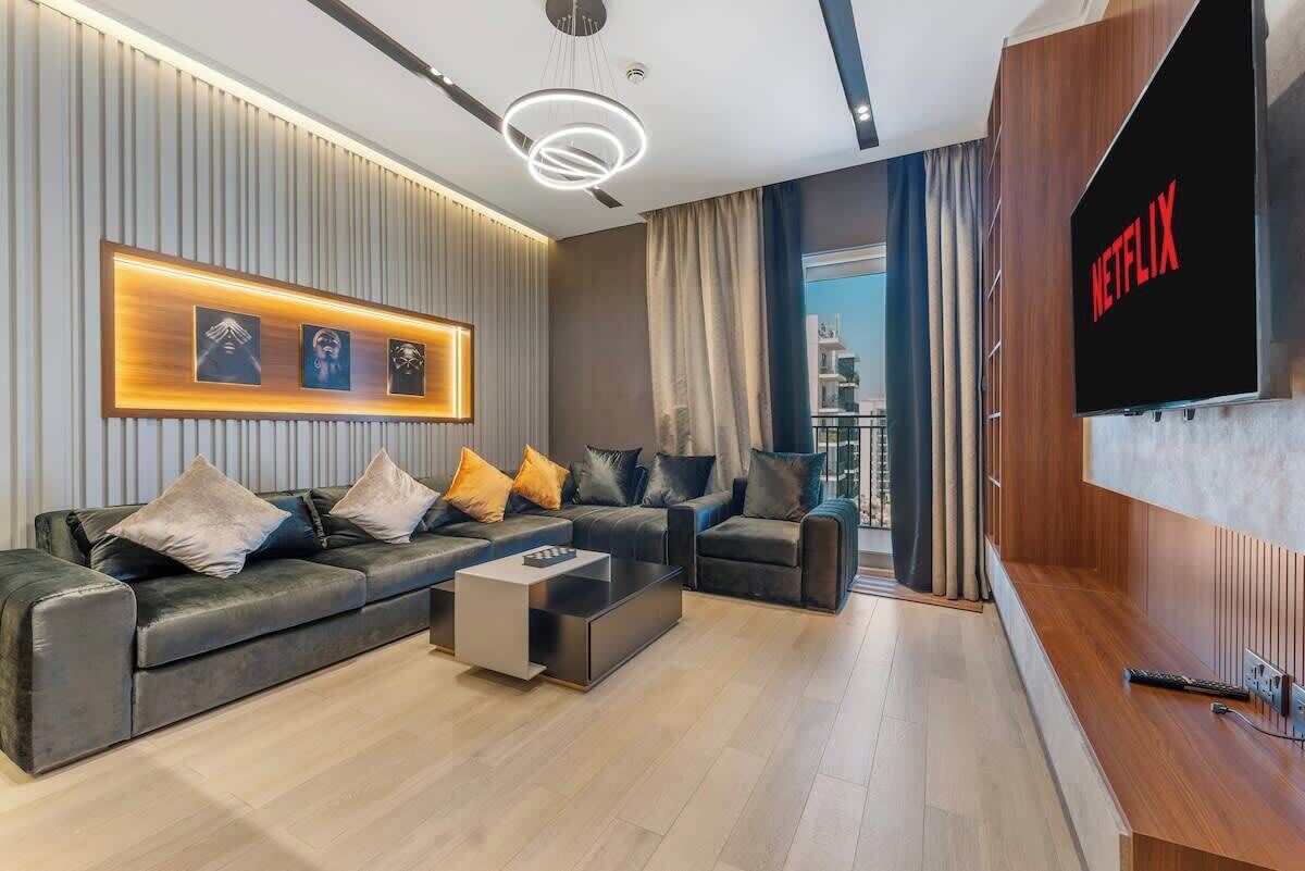 Una sala de estar moderna con un sofá modular, una mesa de centro y un televisor de pantalla plana montado en la pared.