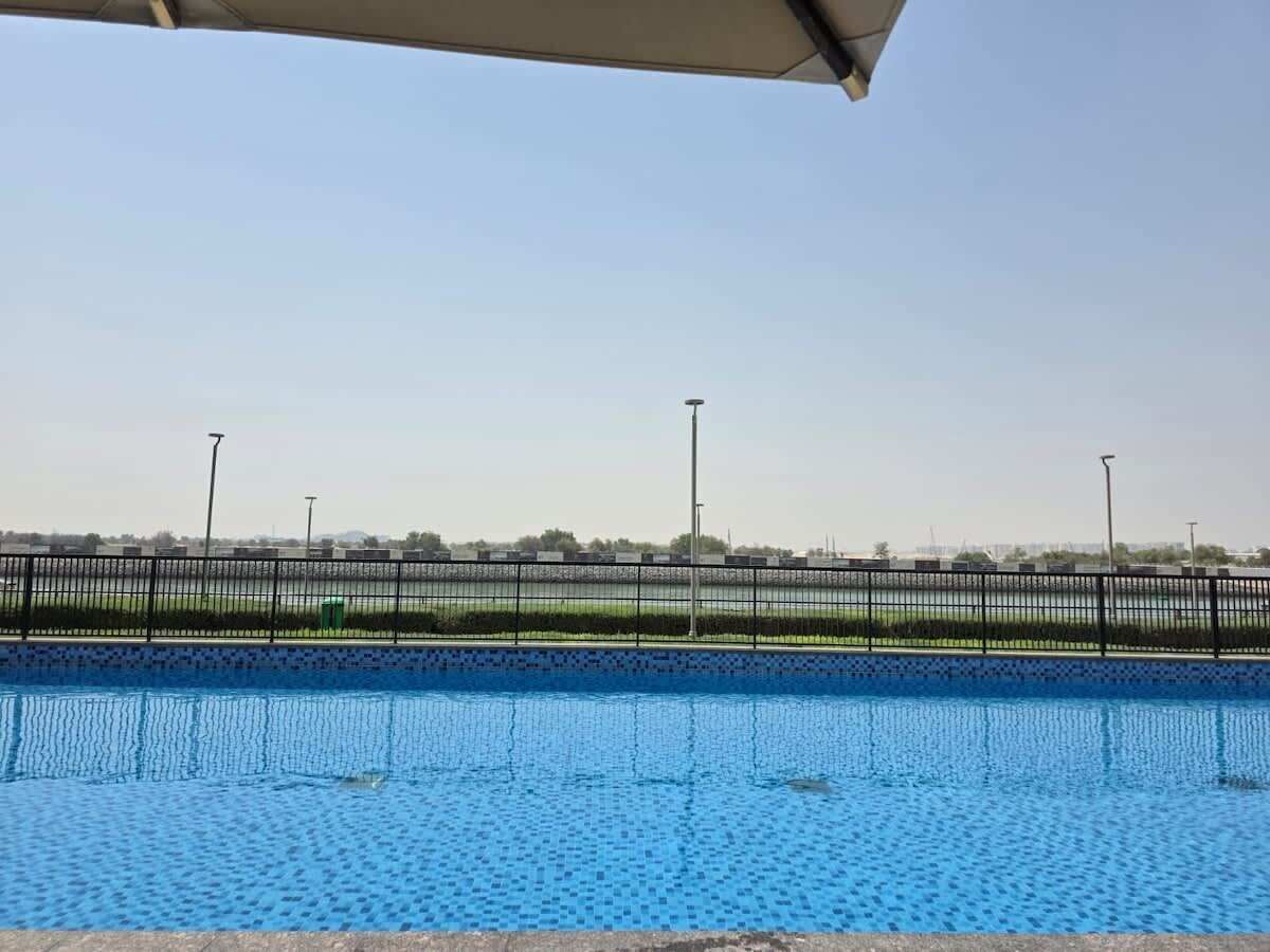 Una piscina amb una vista clara de l'entorn, incloent una tanca i edificis a la distància.