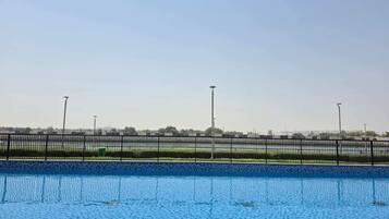Piscina com vista clara da área circundante, incluindo uma grade e edifícios ao longe.