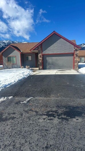 Ein Wohnhaus mit Garage, Auffahrt und verschneiter Landschaft im Hintergrund.
