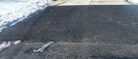 Una casa con garaje, entrada para vehículos y un paisaje nevado al fondo.