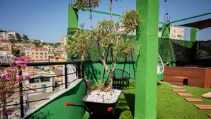 A rooftop garden with a small tree, a wheelbarrow, and a wooden bench. - Rooftop Apartment w Garden Jacuzzi (Durrës)