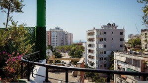 A residential area with multi-story buildings, a green vertical structure, and a balcony with a railing. - Rooftop Apartment w Garden Jacuzzi (Durrës)