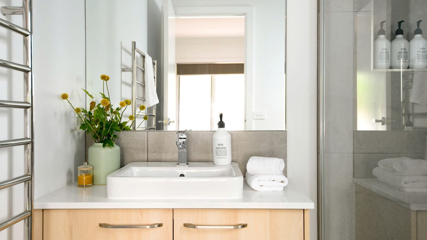 A bathroom with a sink, mirror, towel rack, and toiletries.