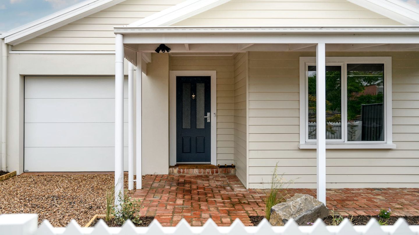 A house with a garage, a covered porch, a front door, and a window.