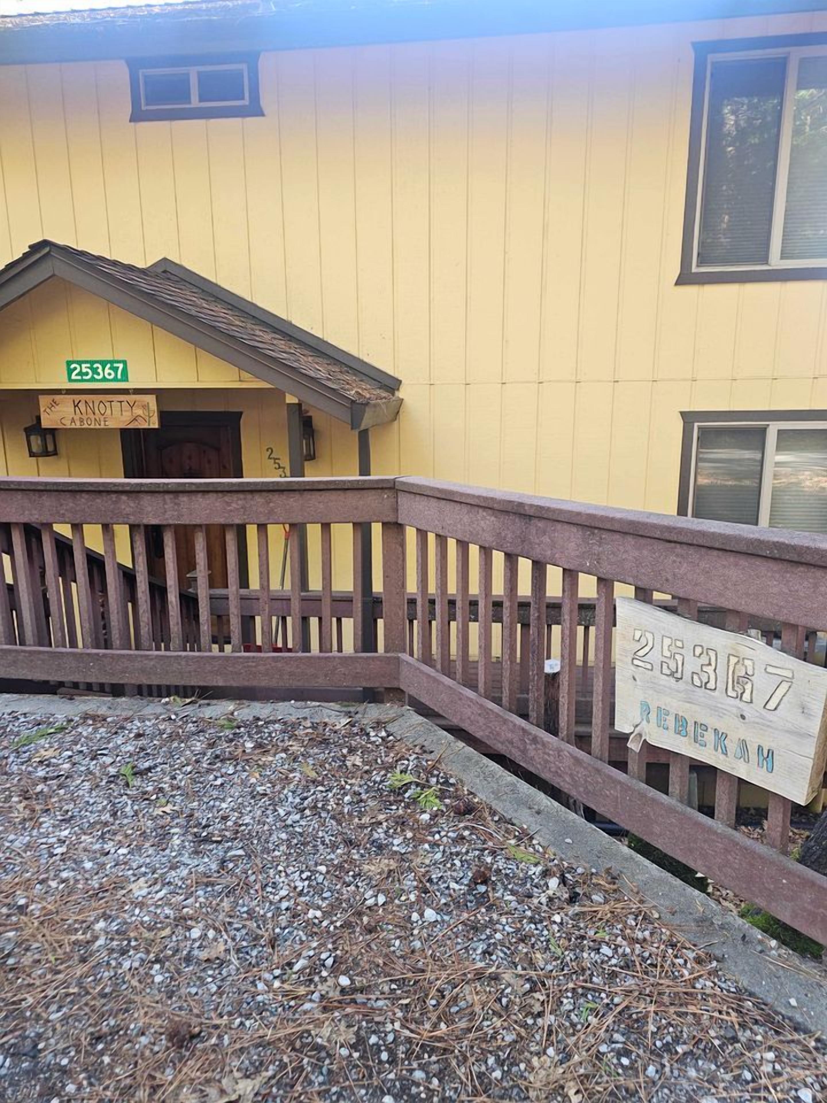 A yellow building with a wooden deck and a sign with the number 25367.