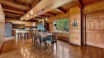 A spacious kitchen with wooden cabinets, a stainless steel refrigerator, and a large island with bar stools.
