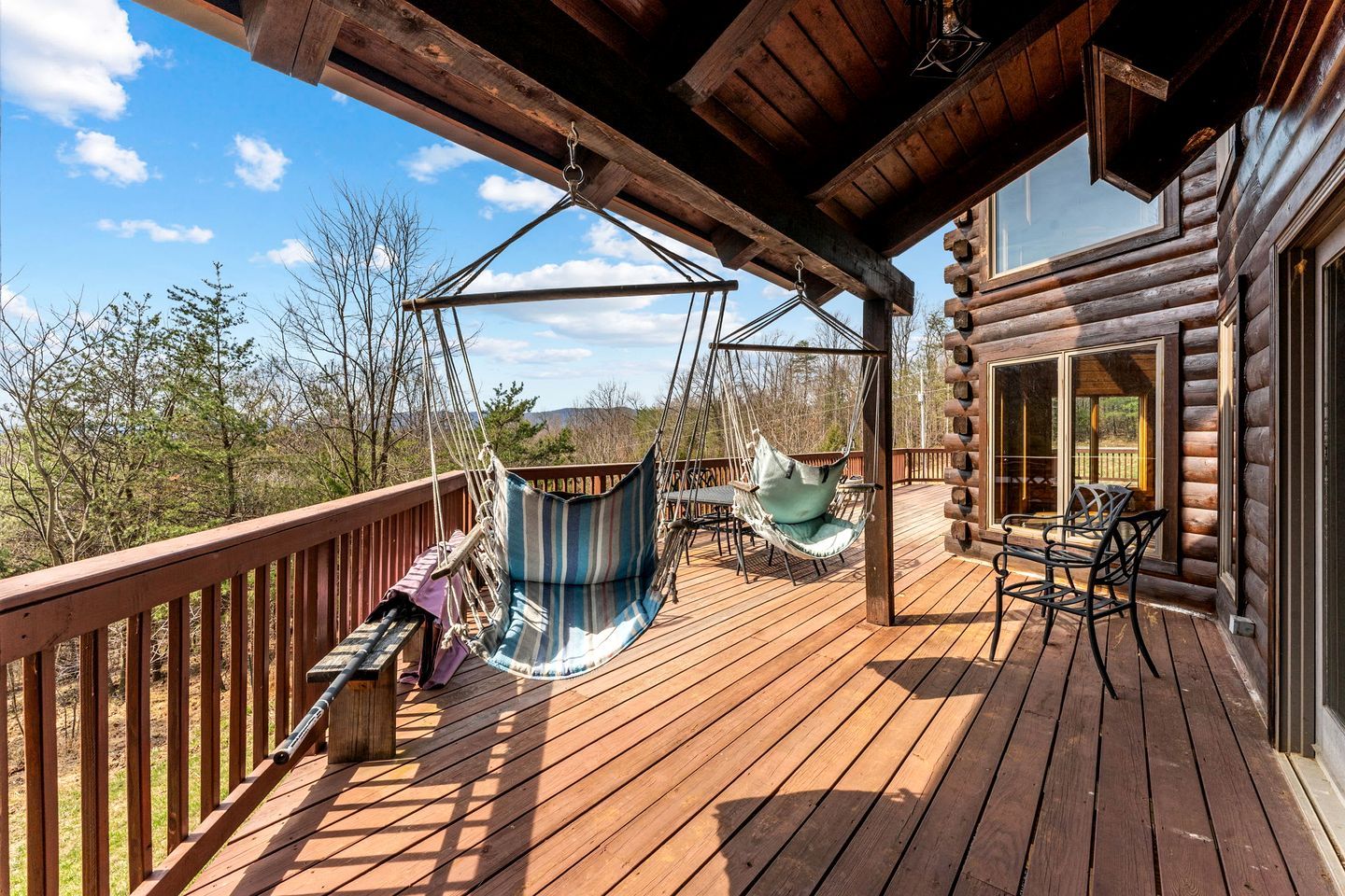 A wooden deck with a hammock, chairs, and a table.