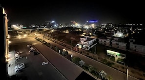 Een nachtzicht van een stadsbeeld met verlichte gebouwen, een weg met geparkeerde auto's en een brug in de verte.