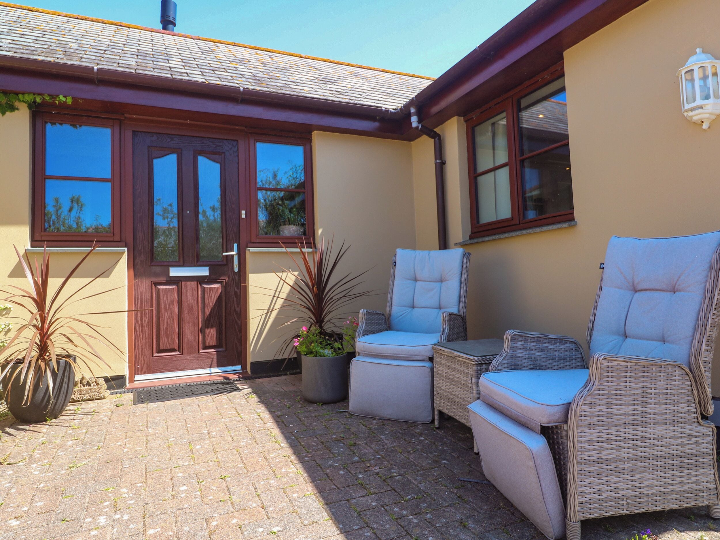 A patio with wicker furniture and potted plants.