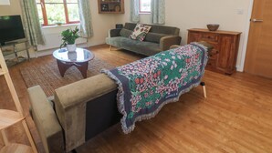 Una sala de estar con un sofá, un televisor, una mesa de centro y un aparador.