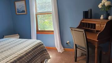 A bedroom with a bed, a desk, a window with curtains, and a ceiling light.
