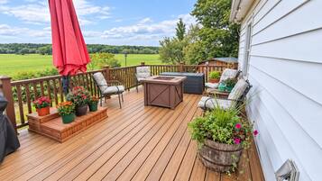 Eine Holzterrasse mit Gartenmöbeln, darunter Stühle und ein Tisch, sowie Kübelpflanzen.