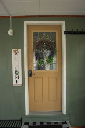 A brown door with a glass panel, a wreath, and a 'WELCOME' sign.
