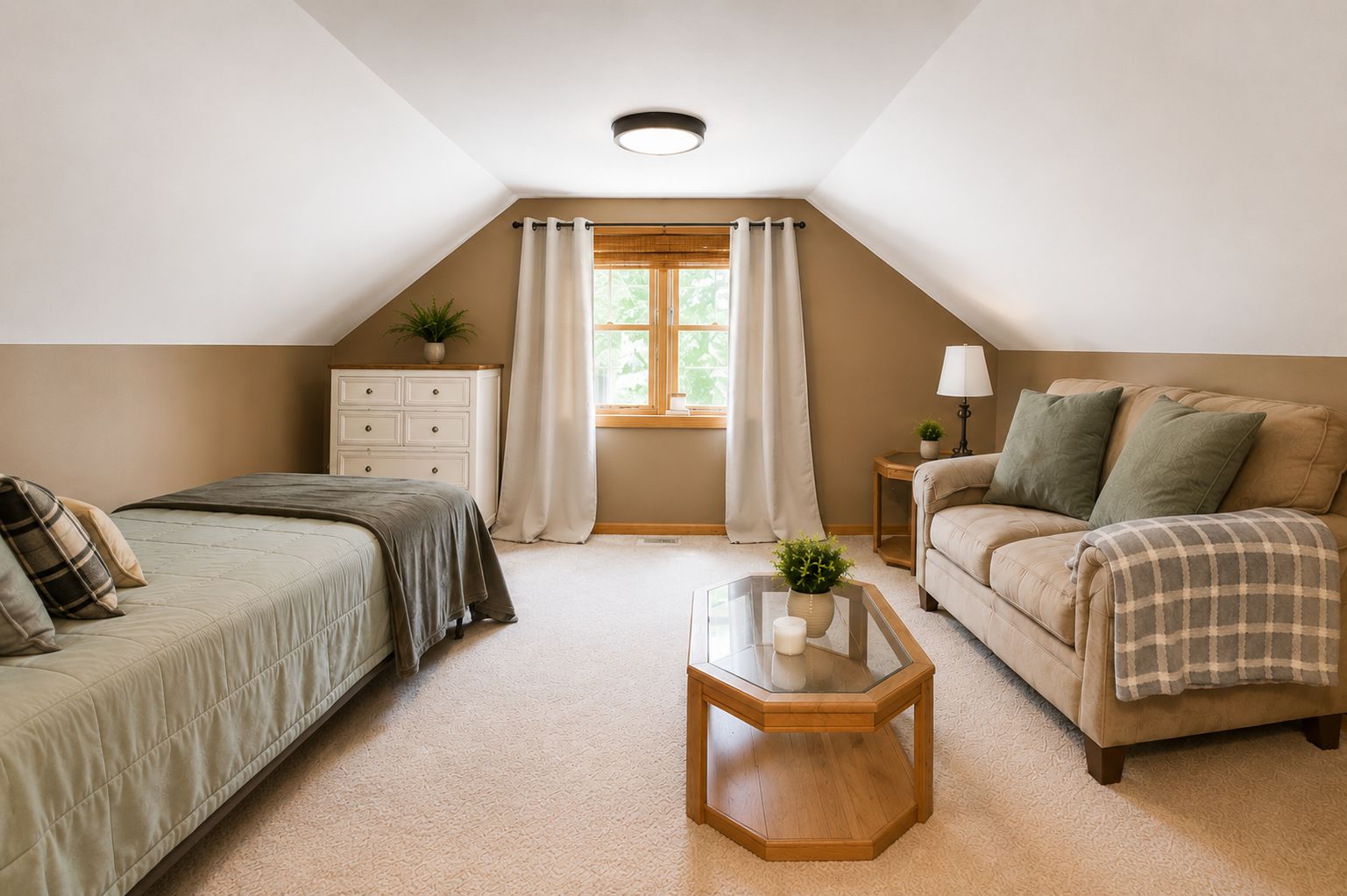 Une chambre à coucher comprenant un lit, un canapé, une table de chevet, une fenêtre avec des rideaux et un luminaire au plafond.