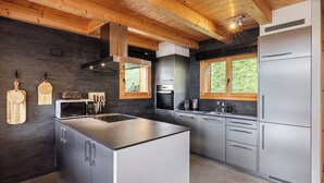 A modern kitchen with a central island, stainless steel appliances, and wooden beams.