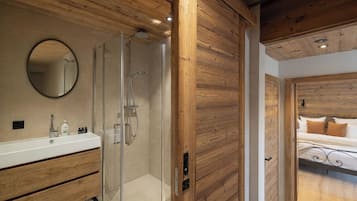A modern bathroom with a glass shower, wooden paneling, a round mirror, and a white sink.
