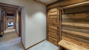 A hallway with a wooden door and a bench, leading to a bedroom with a bed. - Chalet Montâme - Modern Luxury in the Swiss Alps (Riddes)
