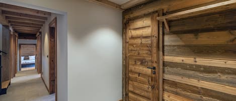 Un corridoio con una porta in legno e una panca, che conduce a una camera da letto con un letto.